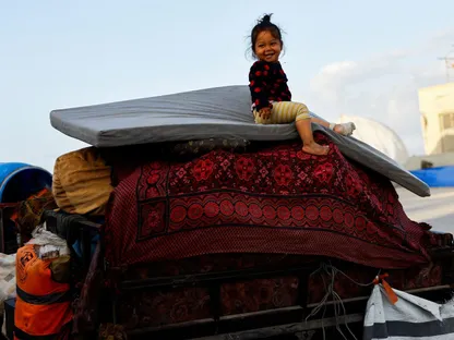 طفلة فلسطينية تجلس فوق ما تبقى من أثاث عائلتها النازحة خلال رحلة العودة إلى شمال غزة، بعد انسحاب إسرائيلي تدريجي، بموجب خطة ترمب، 10 أكتوبر 2025. - REUTERS