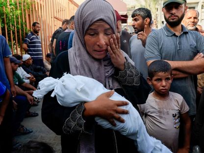 أم فلسطينية تحمل طفلها الرضيع الذي تُوفي بسبب التجويع الإسرائيلي لقطاع غزة. 20 يوليو 2025 - Reuters
