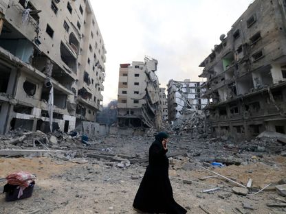 فلسطينية تعبر شارعاً دمرت الغارات الإسرائيلية مبانيه بالكامل في قطاع غزة. 10 أكتوبر 2023 - AFP
