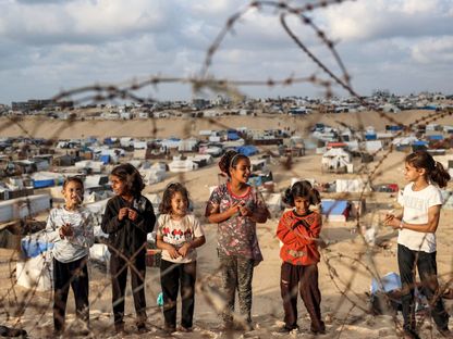 أطفال فلسطينيون يلعبون أمام الخيام التي نزحوا إليها مع عائلاتهم في رفح جنوبي قطاع غزة بينما تستعد إسرائيل لاجتياح المدينة التي تؤوي أكثر من 1.5 مليون نازح. 30 أبريل 2024 - AFP