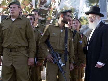حاخام يتحدث إلى جندي إسرائيلي من الكتيبة الحريدية "نيتسح يهودا" خلال مراسم أداء اليمين في تلة الذخيرة في القدس. 26 مايو 2013 - AFP