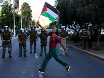 متظاهر يحمل العلم الفلسطيني خلال مسيرة للتضامن مع قطاع غزة أمام السفارة الإسرائيلية في عاصمة تشيلي سانتياجو. 4 مارس 2024 - REUTERS