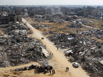 فلسطينيون يسيرون وسط أنقاض المباني المدمرة جراء الحرب الإسرائيلية في رفح جنوب قطاع غزة. 4 فبراير 2025 - REUTERS