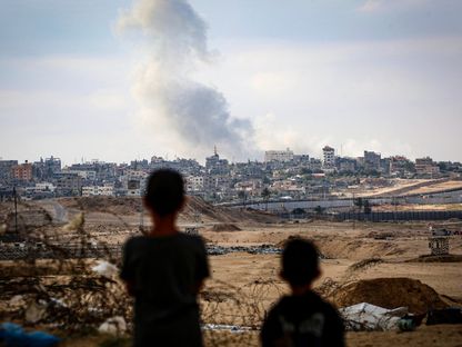 أطفال يشاهدون دخاناً يتصاعد خلال غارات إسرائيلية شرقي رفح في جنوب قطاع غزة. 13 مايو 2024 - AFP