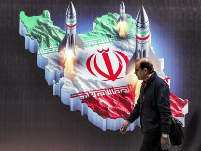 رجل يمشي بالقرب من لافتة تجسد إطلاق صواريخ تحمل ألوان العلم الإيراني من مجسم لخريطة إيران. طهران، إيران. 15 أبريل 2024 - AFP