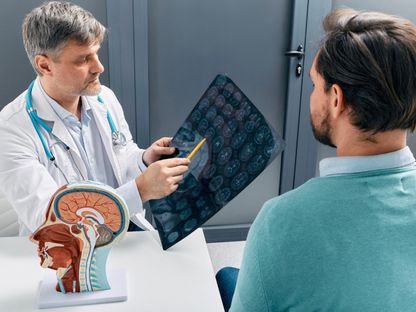 طبيب أعصاب يوضح لمريض نتائج الفحص بالأشعة المقطعية على المخ. 9 أغسطس 2023 - AFP