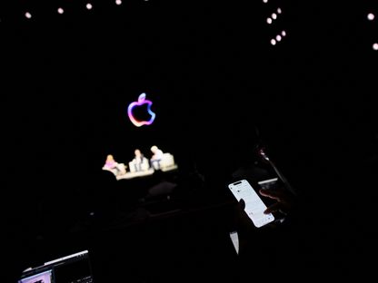 شخص يستخدم هاتفه الذكي خلال مؤتمر أبل للمطورين السنوي WWDC 2024 في ولاية كاليفورنيا الأميركية. 10 يونيو 2024 - AFP
