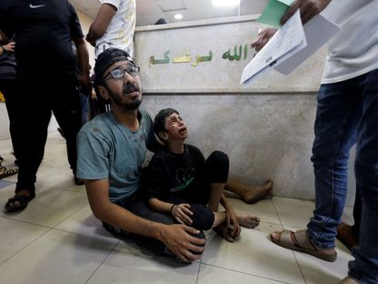 فلسطيني يجلس مع طفل أصيب في غارة إسرائيلية على مستشفى ناصر في خان يونس جنوب قطاع غزة. 18 نوفمبر 2023 - رويترز