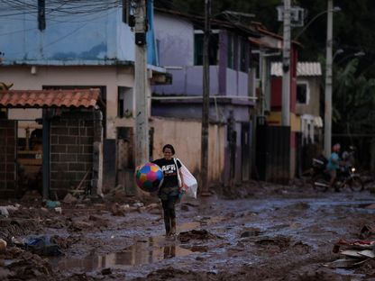 امرأة تمشي في الوحل وسط الدمار الذي سببته الفيضانات الناجمة عن الأمطار الغزيرة في هونوريو بيكالو بالبرازيل. 12 يناير 2022 - AFP