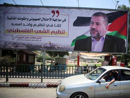 فلسطينيون يسيرون أمام لوحة إعلانية تحمل صورة القيادي في حركة "حماس" صالح العاروري في غزة. 27 أغسطس 2023 - AFP