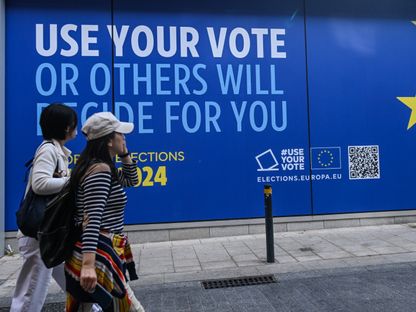 اثنان من المارة يسيران أمام مركز زوار "تجربة أوروبا" في دبلن والذي يعلن عن انتخابات البرلمان الأوروبي المقررة في 7 يونيو. 21 مايو 2024 - AFP