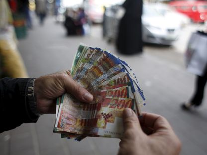 فلسطيني يعد نقوداً في سوق بمدينة رام الله في الضفة الغربية المحتلة. 25 مارس 2015 - Reuters