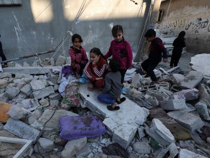 أطفال فلسطينيون يجلسون فوق ركام منزلهم الذي دمرته غارات إسرائيلية على رفح جنوب القطاع. 29 ديسمبر 2023 - REUTERS