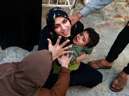 فلسطينية تحمل طفلها وتبكي في انتظار جثة طفلتها التي قتلتها الغارات الإسرائيلية على رفح، جنوب قطاع غزة. 1 ديسمبر 2023 - AFP