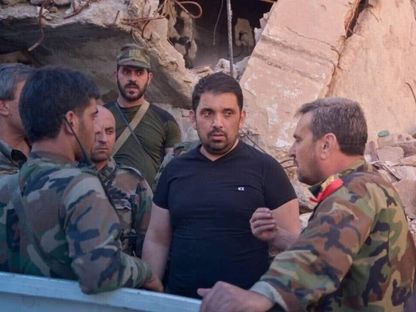 'فادي صقر' قائد 'الدفاع الوطني' في دمشق خلال حكم نظام الأسد في صورة غير مؤرخة يرتدي الزي المدني وسط مجموعة من الضباط والجنود - "مواقع التواصل"