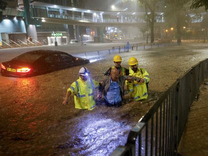 رجال إنقاذ يساعدون مسناً صينياً على النجاة من فيضان ناتج عن أمطار غزيرة في هونج كونج بالصين. 8 سبتمبر 2023 - REUTERS