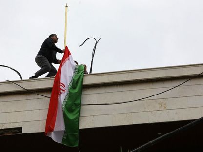 موظف يرفع علم إيران على مبنى قنصلية طهران الجديد في العاصمة السورية دمشق بعد تدمير المبنى القديم في غارة إسرائيلية. 8 أبريل 2024 - AFP