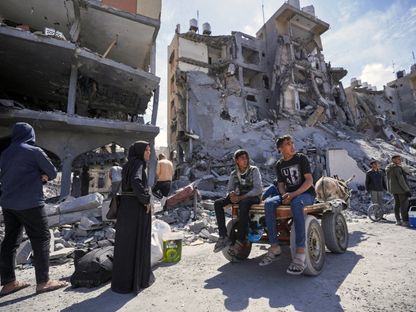 نازحون فلسطينيون يجمعون متعلقاتهم أمام منازل دمرتها الغارات الإسرائيلية على خان يونس جنوبي قطاع غزة. 14 مارس 2024 - AFP