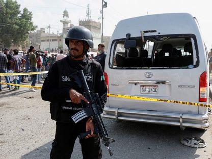 ضابط شرطة يقف بالقرب من سيارة متضررة محاطة بسياج في موقع تفجير انتحاري في كراتشي. 19 أبريل 2024 - Reuters