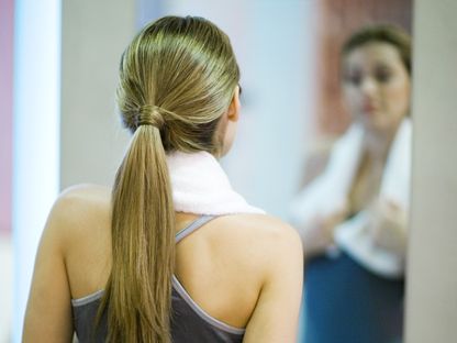 امرأة شابة رياضية تنظر إلى نفسها في المرآة. 11 يونيو 2009 - AFP