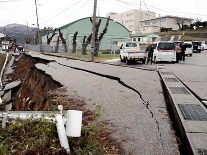 أشخاص يقفون بجوار شقوق كبيرة في الرصيف بعد إخلاء منازلهم في مدينة واجيما بمحافظة إيشيكاوا في أعقاب زلزال ضرب وسط اليابان. 1 يناير 2024 - AFP