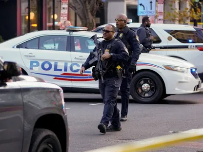 عناصر إنفاذ القانون يسيرون خلف شريط تحذيري أصفر مع مركبة شرطة متوقفة خلفهم بعد أن أُصيب عضوان من الحرس الوطني في إطلاق نار بالقرب من البيت الأبيض في واشنطن، الولايات المتحدة. 26 نوفمبر 2025 - Reuters