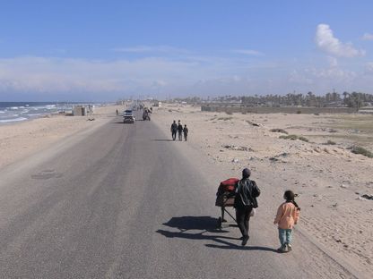 نازحون فلسطينيون يسيرون على طول الطريق الساحلي قبل العمليات البرية العسكرية الإسرائيلية غرب رفح وخان يونس في المواصي بغزة. 15 فبراير 2024 - Bloomberg