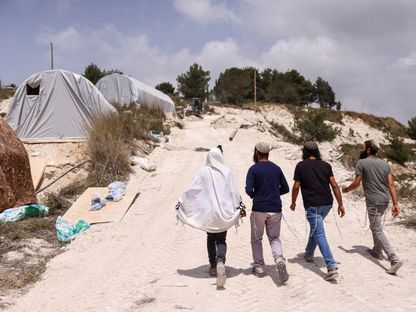 مستوطنون إسرائيليون يسيرون قرب بؤرة استيطانية بالضفة الغربية التي تحتلها إسرائيل. 29 مايو 2023 - Reuters