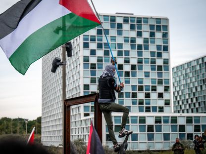 متظاهر يرفع العلم الفلسطيني أمام مقر محكمة العدل الدولية في لاهاي بهولندا. 18 أكتوبر 2023 - AFP