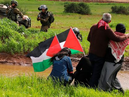 جنود إسرائيليون يصوبون أسلحتهم تجاه متظاهرين فلسطينيين يحتجون على خطة إسرائيل لضم أراضٍ من الضفة الغربية المحتلة. 29 فبراير 2020. - AFP