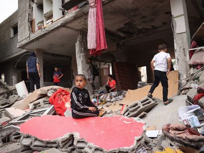 أطفال فلسطينيون وسط أنقاض منزل دمره القصف الإسرائيلي ليلاً في رفح بجنوب قطاع غزة. 27 أبريل 2024 - AFP