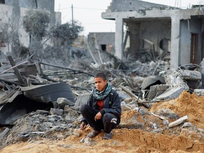 طفل فلسطيني يجلس وسط أنقاض منزل دمرته غارة إسرائيلية في مدينة رفح بجنوب قطاع غزة. 23 فبراير 2024 - Reuters
