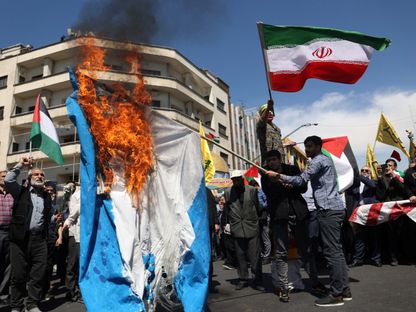 إيرانيون يحرقون العلم الإسرائيلي خلال جنازة عناصر الحرس الثوري الذين سقطوا في الضربة الإسرائيلية على قنصلية طهران بدمشق. 5 أبريل 2024 - Reuters