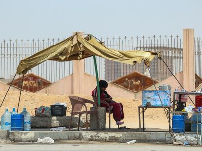 بائعة تجلس محتمية من حرارة الشمس في أحد شوارع ضواحي القاهرة بمصر - Bloomberg