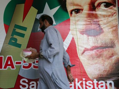 رجل يسير بجوار صورة نجم الكريكت عمران خان رئيس حركة الإنصاف الباكستانية في أحد أسواق إسلام أباد- 27 يوليو 2018 - Reuters