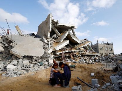 فتاتان فلسطينيتان تجلسان بجانب منزل مدمر في رفح جنوب قطاع غزة. 21 أبريل 2024 - REUTERS