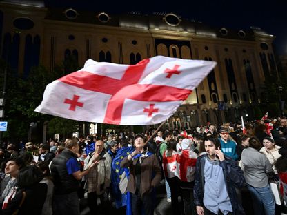 متظاهر يلوح بعلم جورجيا خلال مظاهرات ضد قانون 'العميل الأجنبي'، خارج البرلمان الجورجي في العاصمة تبليسي، 18 مايو 2024 - AFP