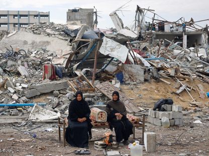 سيدتان فلسطينيتان تجلسان أمام أنقاض مبنى دمرته غارات إسرائيلية في رفح جنوبي قطاع غزة. 22 يناير 2025 - Reuters