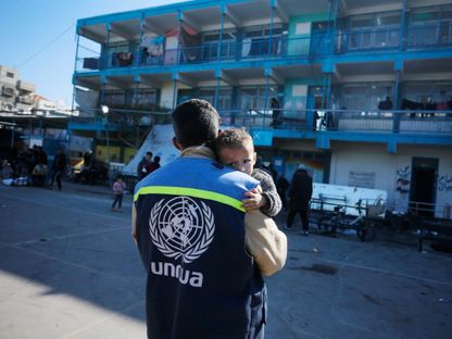 موظف تابع لوكالة الأونروا يحمل طفل في قطاع غزة.  27 يناير 2024 - facebook/unrwa