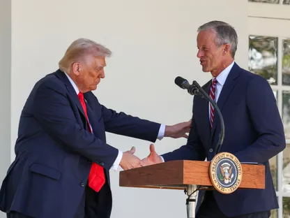 الرئيس الأميركي دونالد ترمب يصافح زعيم الأغلبية في مجلس الشيوخ الأميركي جون ثون في البيت الأبيض بواشنطن العاصمة في الولايات المتحدة. 21 أكتوبر 2025 - REUTERS