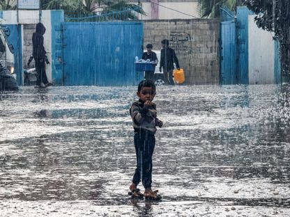 طفل يقف تحت المطر في ساحة مدرسة تابعة للأونروا في غزة. 14 نوفمبر 2023 - AFP