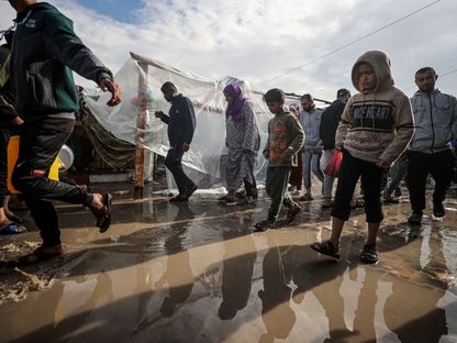 نازحون فلسطينيون في غزة يحاولون تفادي مياه الأمطار داخل مخيم لإيواهم وسط القصف الإسرائيلي المستمر على القطاع. 15 نوفمبر 2023 - AFP
