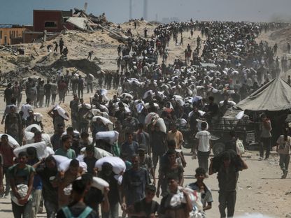 فلسطينيون يسيرون على الأقدام عقب الحصول على مساعدات غذائية في بيت لاهيا شمال قطاع غزة. 27 يوليو 2025 - REUTERS