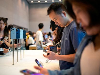 أشخاص يفصحون أجهزة آيفون 15 داخل أحد متاجر شركة أبل في شنغهاي بالصين. 22 سبتمبر 2023 - Reuters