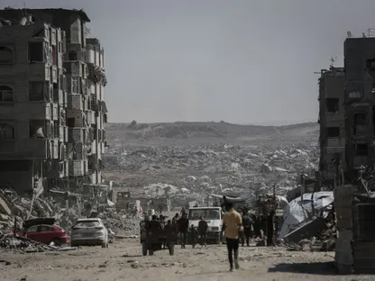 فلسطينيون نازحون يسيرون في شارع بين مبانٍ مدمرة بمدينة غزة. 16 أكتوبر 2025 - Bloomberg