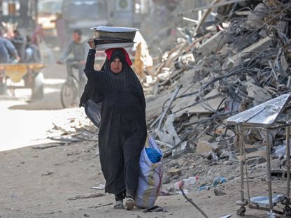 سيدة فلسطينية تحمل أغراضها في خان يونس وتحاول النزوح إلى مناطق آمنة بينما يستمر القصف الإسرائيلي والغارات على قطاع غزة. 6 مارس 2024 - AFP