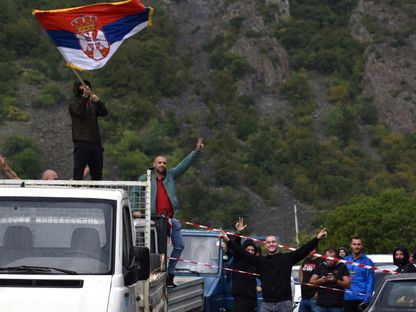 أحد صرب كوسوفو يلوح بالعلم الصربي بينما يحتج الناس على الحظر الحكومي على دخول المركبات التي تحمل لوحات تسجيل صربية في جارينجي، كوسوفو، 20 سبتمبر 2021 - Reuters