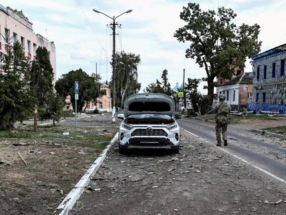 جندي أوكراني يقوم بدورية في شارع بجوار مبانٍ تضررت جراء القتال في بلدة سودجا التي تسيطر عليها أوكرانيا في منطقة كورسك الروسية. 16 أغسطس 2024 - REUTERS