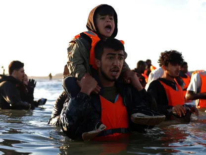 مهاجرون يخوضون في مياه البحر في محاولة للصعود على متن زورق مطاطي يغادر ساحل شمال فرنسا للوصول إلى بريطانيا. 25 أغسطس 2025 - Reuters