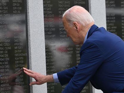 الرئيس الأمريكي جو بايدن بضع يده على اسم عمله المحارب القديم في الحرب العالمية الثانية، أمبروز فينيجان، في نصب تذكاري في سكرانتون ببنسلفانيا. 17 أبريل 2024 - AFP